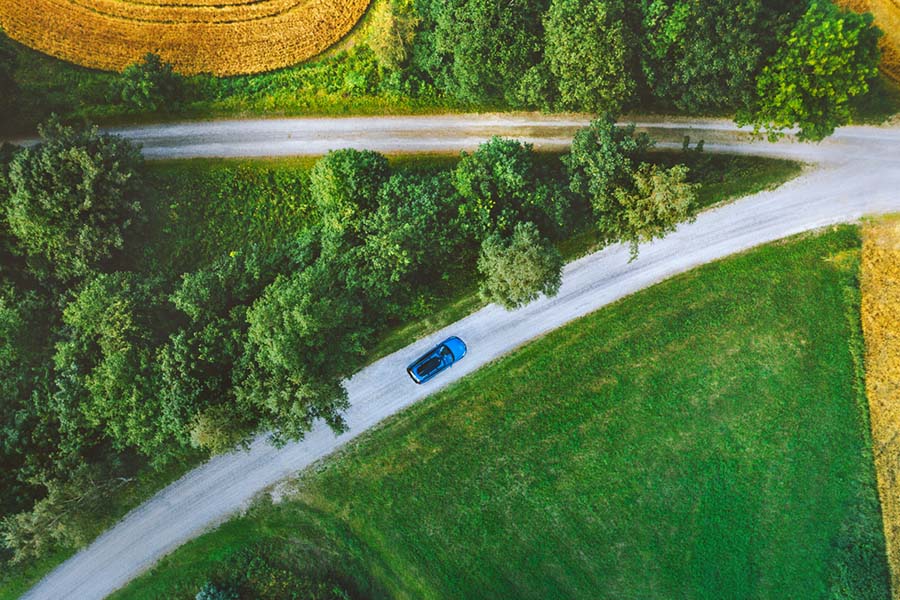 aerial view of an electric car driving through green fields