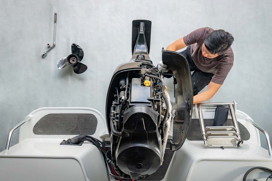 man fixing outboard motor of a boat