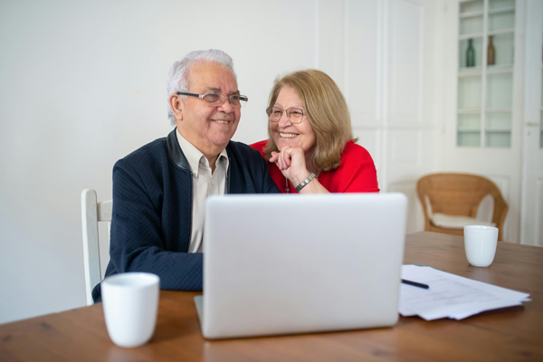 older couple smiling at table with laptop