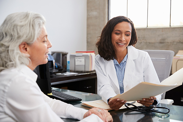 smiling female doctor in consultation with senior